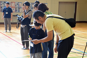 写真：感想を話し合いながら紙に書く父子